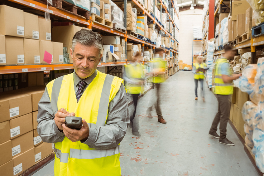 Workers organizing shelves with yellow caution vests on.
